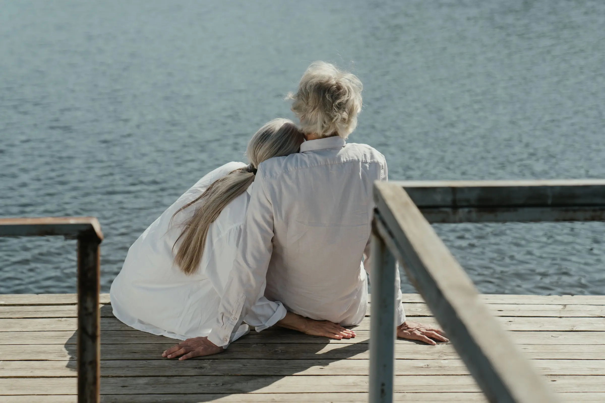 Eldre par sitter på en brygge og ser utover vannet, illustrerer et langt og aktivt liv