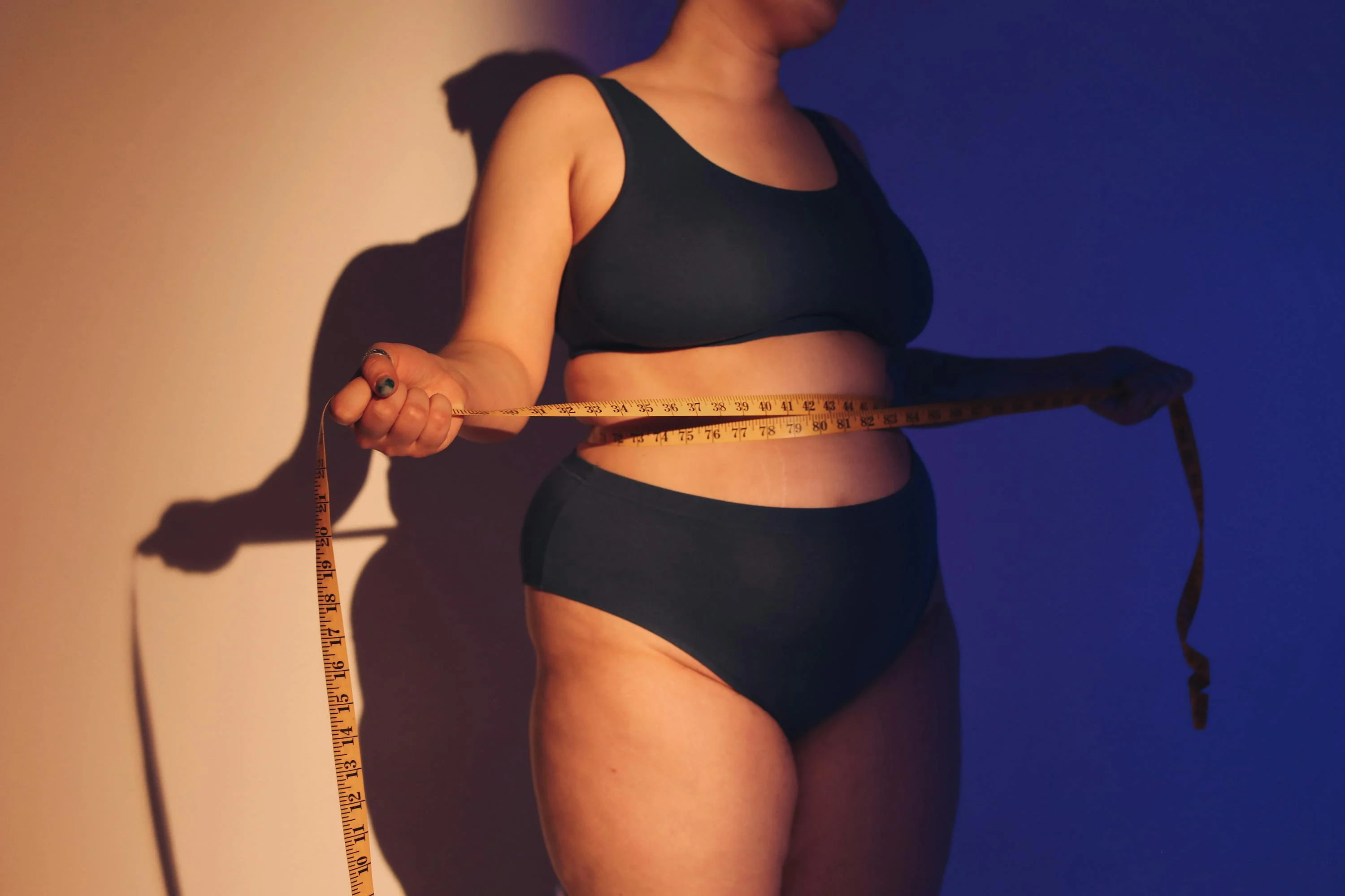 Person måler midjen med målebånd, illustrerer fokus på vekt og metabolsk helse